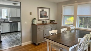 A kitchen with white cabinets, a wooden countertop, and a dining table with white chairs. - Marvelous 4-bedroom, 2-bath home with AC and private backyard close to the beach (Narragansett)