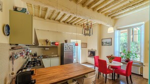 A kitchen with wooden countertops, a dining area with red chairs, and a window with a view of greenery.