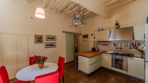 A kitchen with a central island, wooden flooring, and a hanging light fixture.