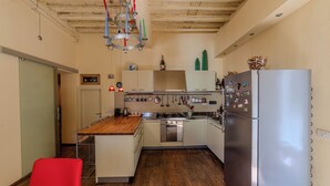 A kitchen with a wooden countertop, stainless steel appliances, and a red chair.