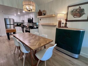 A modern kitchen with white cabinets, a wooden dining table, and a teal accent piece. - Fox Trail Hideaway by Branson Landing-Waterfront (Branson)