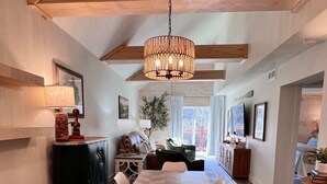 A dining area with a large wooden table, white chairs, and a hanging light fixture. - Fox Trail Hideaway by Branson Landing-Waterfront (Branson)