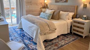 A bedroom with a bed, bedside tables, a nightstand, a window with curtains, and a painting on the wall. - Fox Trail Hideaway by Branson Landing-Waterfront (Branson)