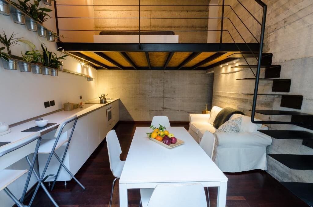 Una cocina moderna con comedor, muebles blancos y una escalera.