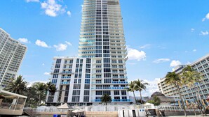 A high-rise hotel with multiple floors, large windows, and a central atrium. - Luxurious 2BD Condo with Direct Ocean Views & Resort Pool - Apartment (Sunny Isles Beach)