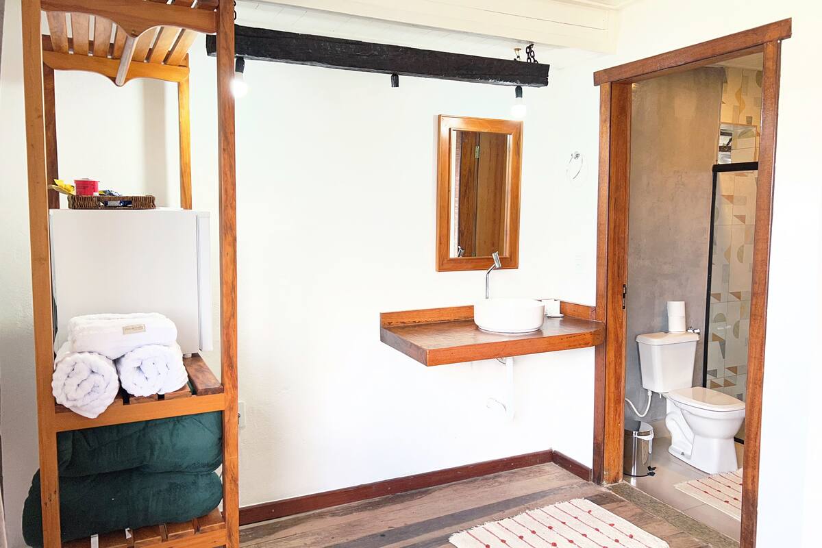 A bathroom with a wooden vanity, a toilet, a towel rack, and a mirror.