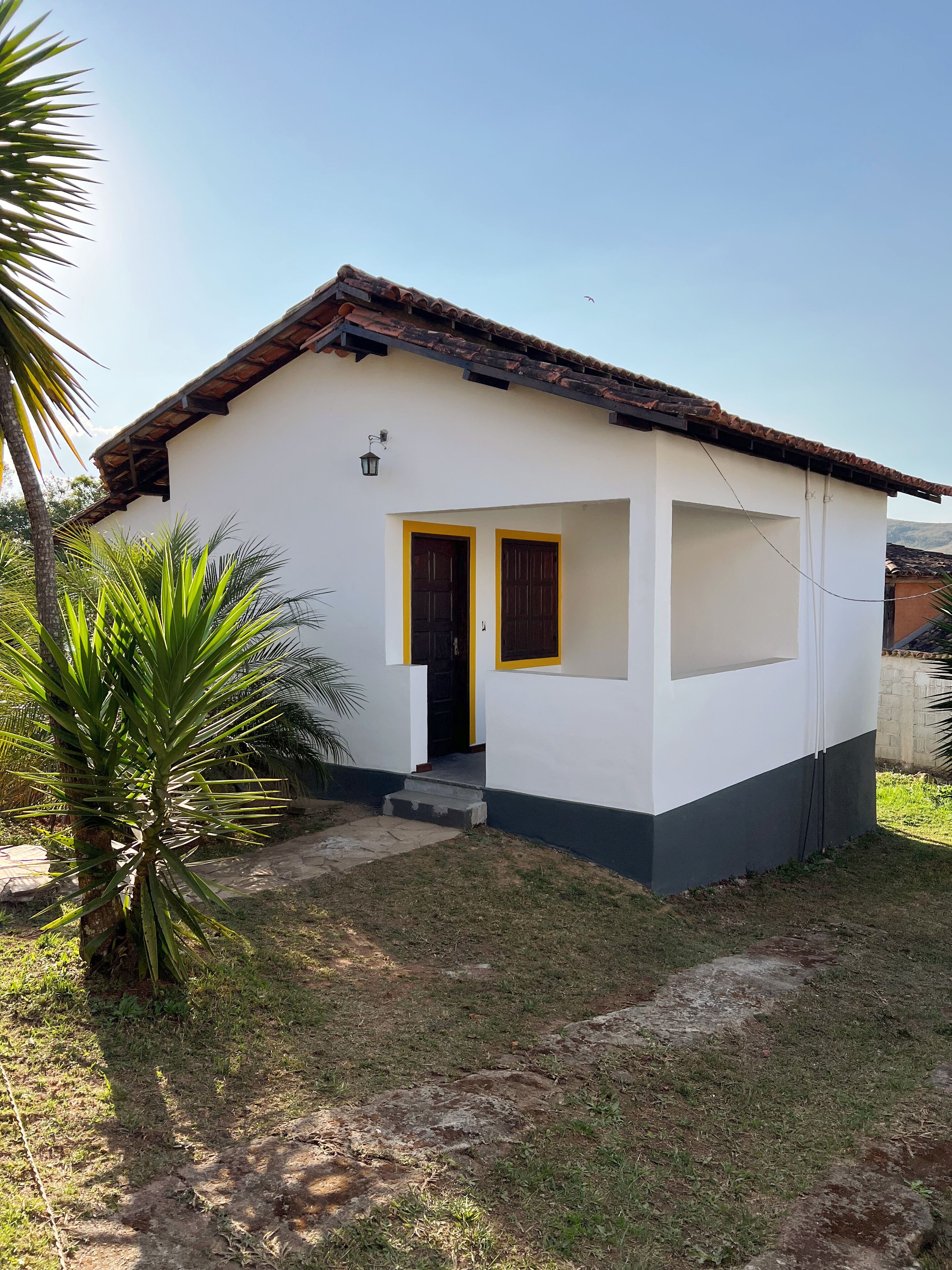 Uma pequena casa térrea com telhado de cerâmica, porta frontal e pequena varanda.