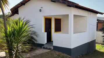 Uma pequena casa térrea com telhado de cerâmica, porta frontal e pequena varanda.