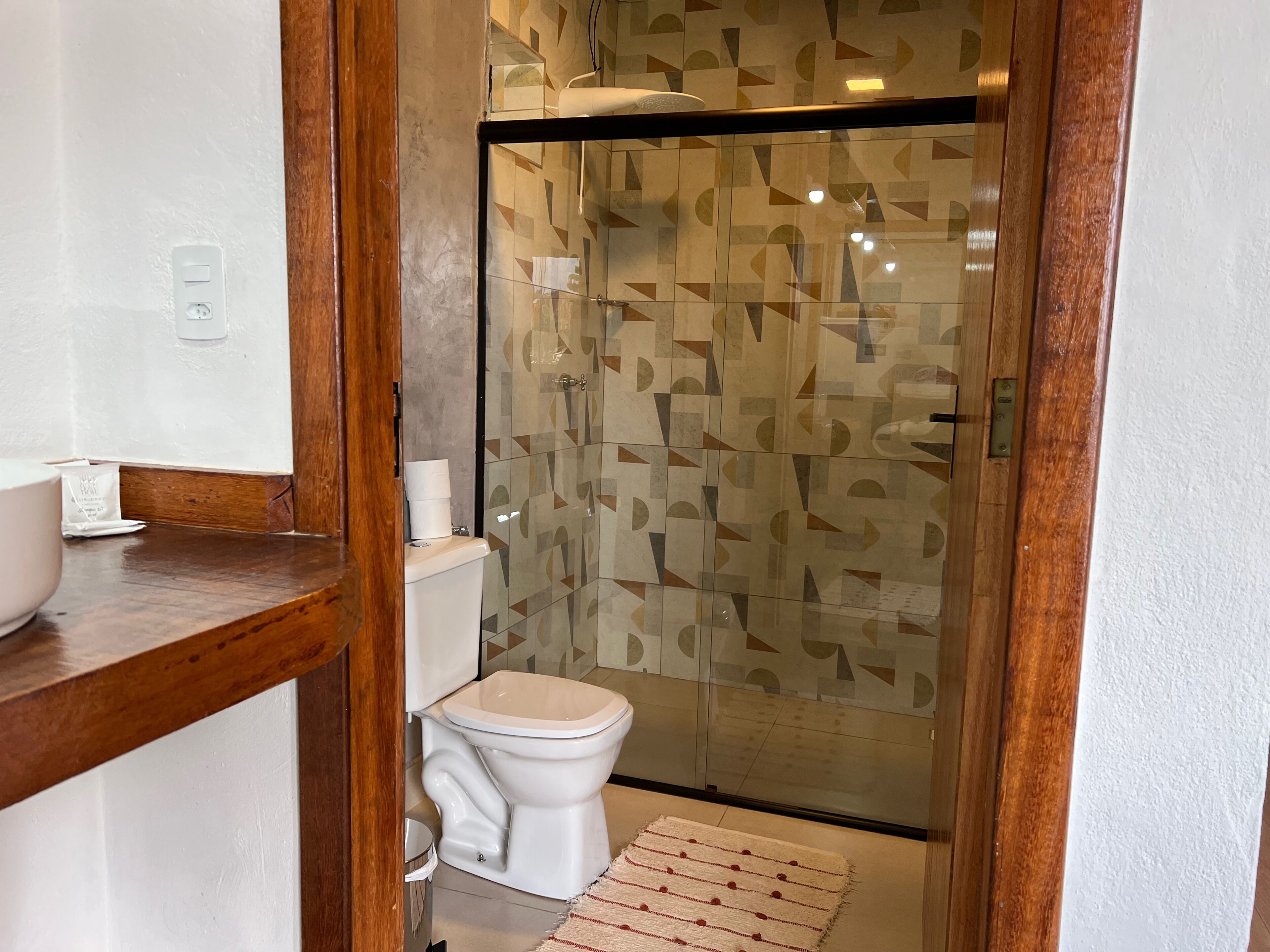 A bathroom with a toilet, a sink, and a shower enclosure.