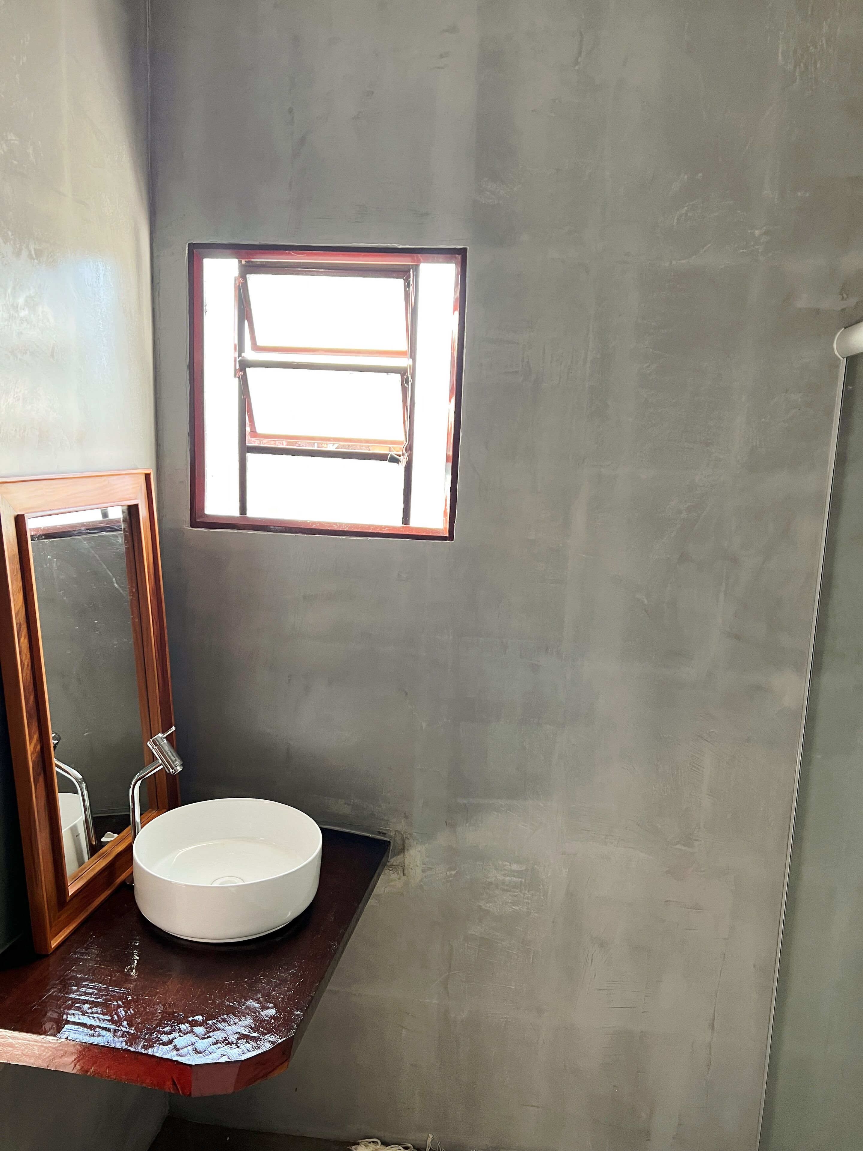 Ein Badezimmer mit einem weißen Waschbecken, einem Spiegel und einem Fenster.
