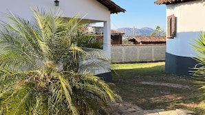 A courtyard with a white building, a stone wall, and a view of mountains in the background. - Pousada Villa Salgueiro (Ouro Preto)