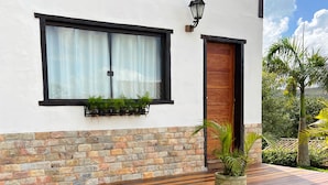 A modern building with a stone facade, a wooden bench, a window with curtains, and a door. - Pousada Villa Salgueiro (Ouro Preto)