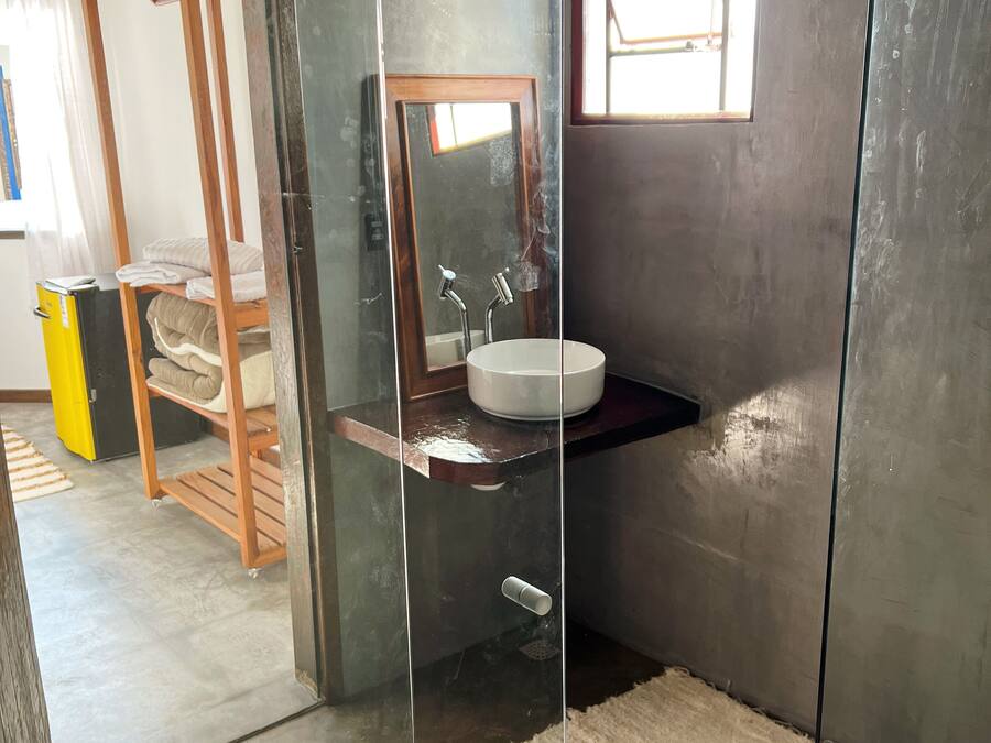 A bathroom with a wooden bench, a sink, and a mirror.