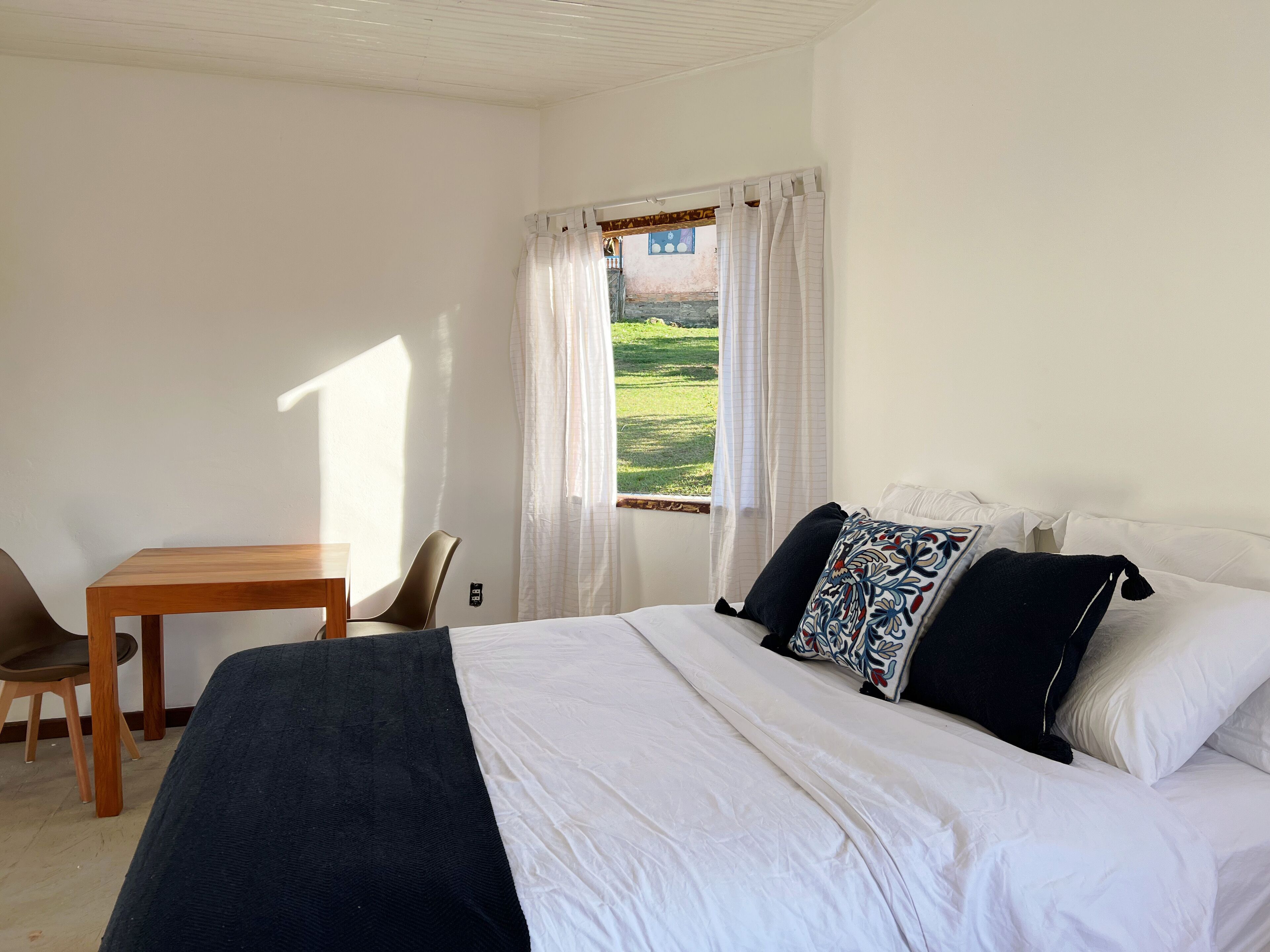 A bedroom with a bed, a wooden table, and a chair.