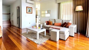Un salon moderne avec un parquet, un canapé blanc, une table basse et une lampe.
