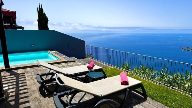 Un espace aménagé au bord de la piscine, avec des chaises longues et une vue sur l’océan.