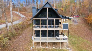 A two-story cabin with a balcony, surrounded by trees and a forested area. - Creeks n' Peaks - Ellijay, GA (Ellijay)