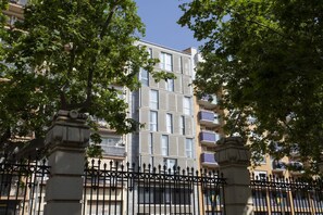A multi-story building with balconies, surrounded by trees and a black wrought iron fence. - La Pergola 2B - Double Studio Exterior (Castelló de la Plana)