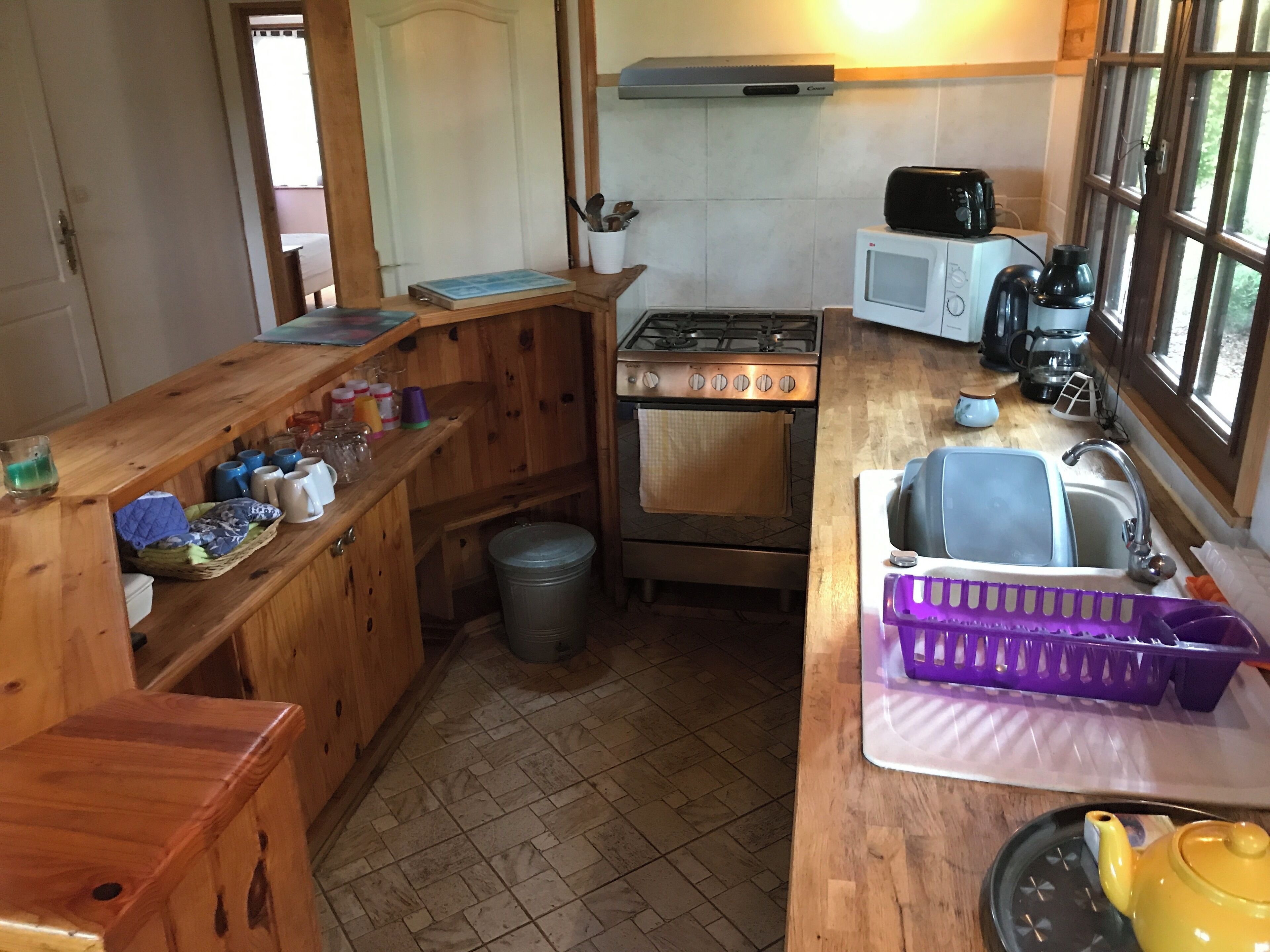 A compact kitchen with a stove, microwave, sink, and wooden cabinetry.