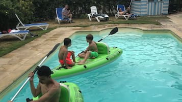 Une piscine où deux personnes sont à bord de kayaks gonflables verts.