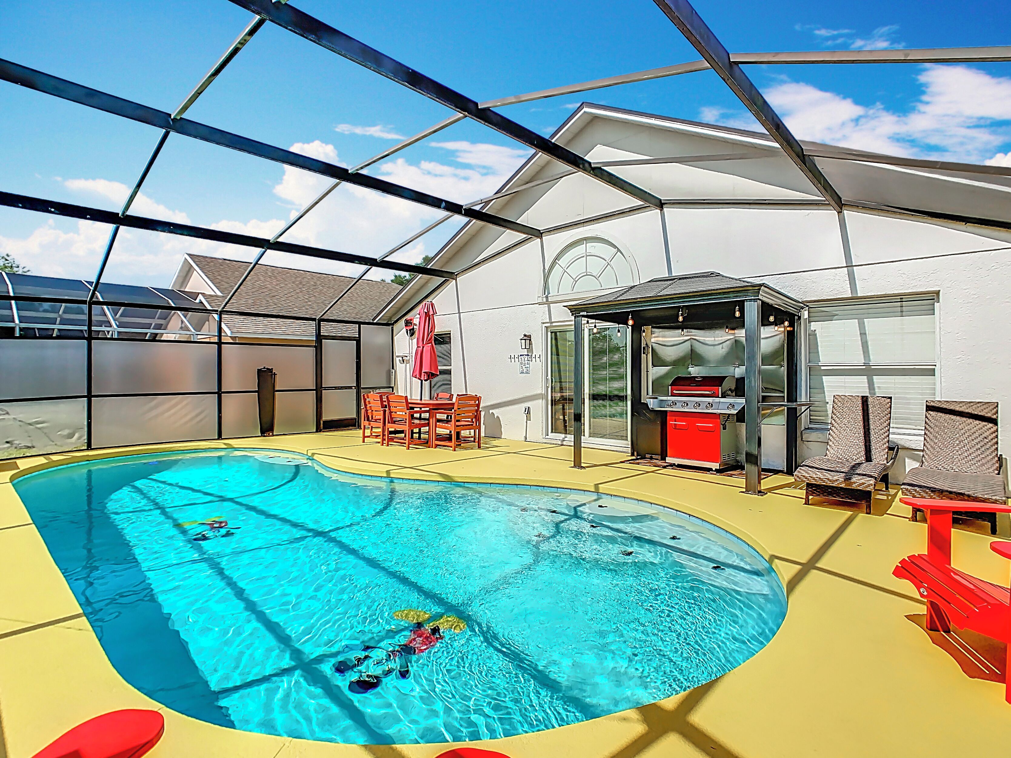 Una piscina interna con un patio coperto, un angolo barbecue e posti a sedere all'aperto.
