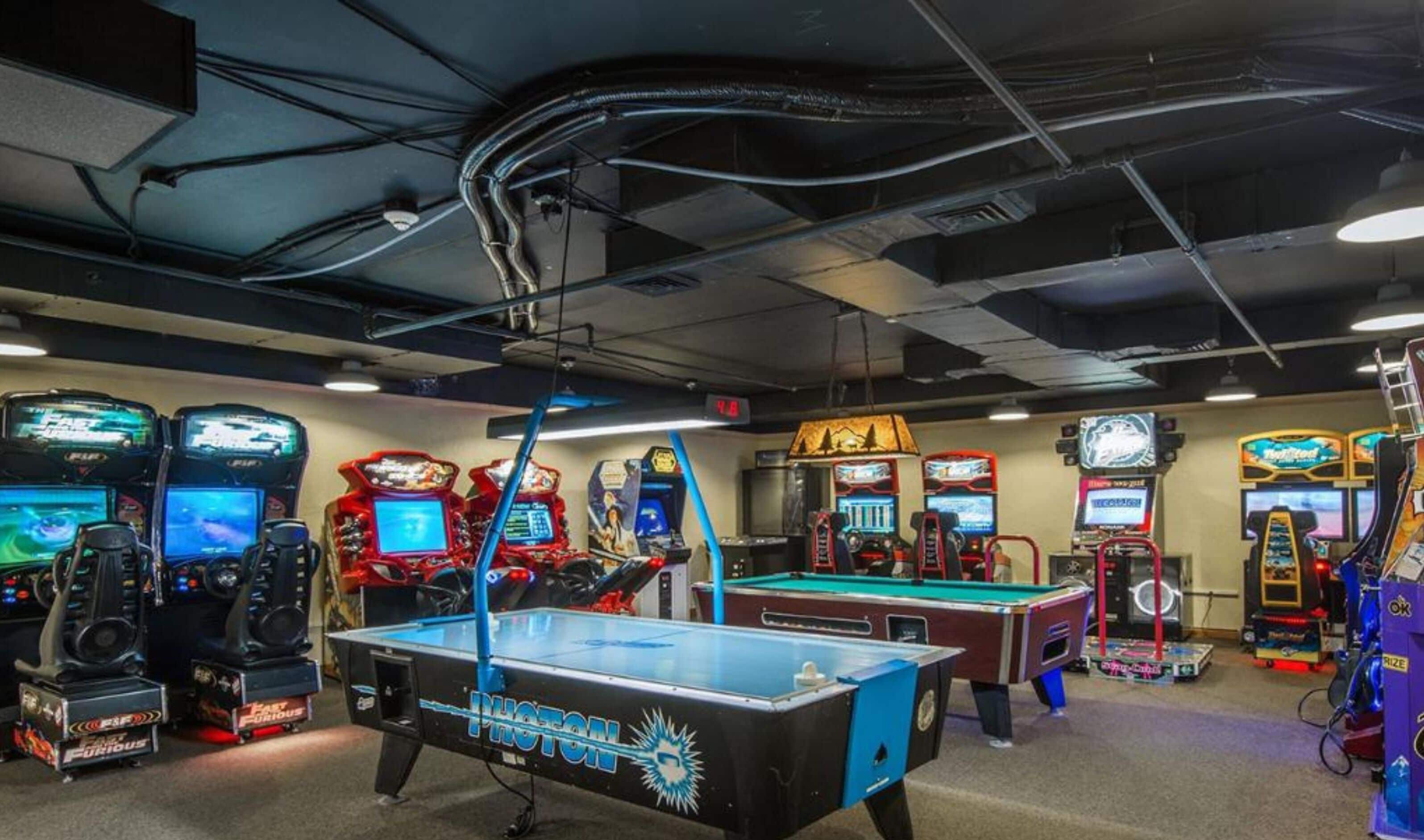 A gaming arcade with various video game machines and a pool table.