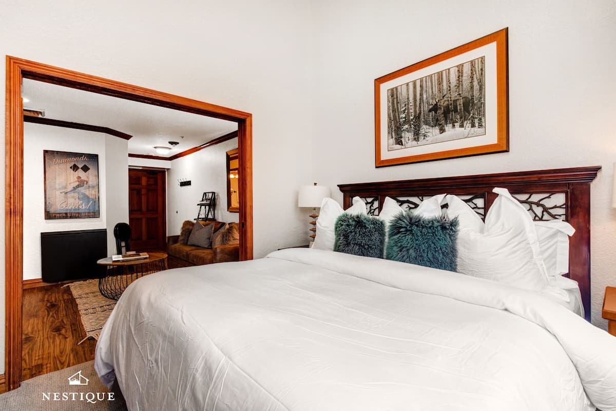 A hotel room with a large bed, a framed picture on the wall, and a wooden headboard.