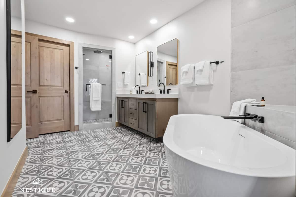 A modern bathroom with a freestanding bathtub, a double sink vanity, and a large mirror.