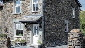 Un edificio de piedra con diseño tradicional, que cuenta con una puerta principal, ventanas y un pequeño porche.