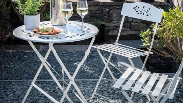 A stone building with a garden patio featuring a round table, two chairs, and potted plants. - Bracken House - Luxury design 3 bed in Windermere (Windermere)