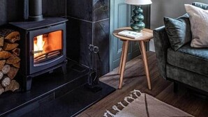 A cozy room with a stone wall, a fireplace, a green door, and a leather sofa. - Bracken House - Luxury design 3 bed in Windermere (Windermere)