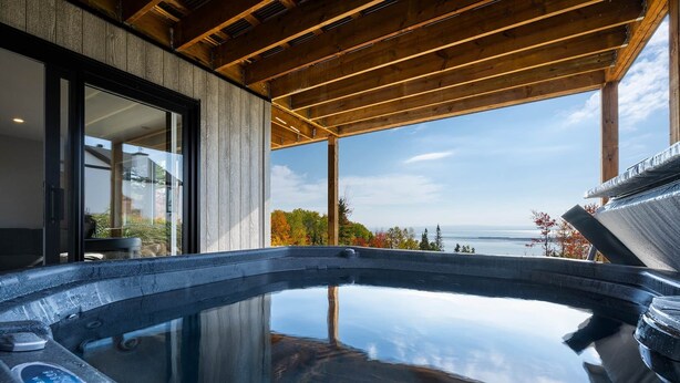 Ein Whirlpool mit Blick auf den Ozean, eine Holzbalkendecke und große Fenster.