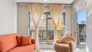 A modern living room with a sofa, a chair, and a large window with curtains. - Maxihomes Bliss (Antalya)