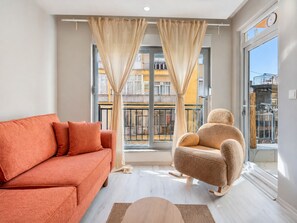 A modern living room with a sofa, a chair, and a large window with curtains.