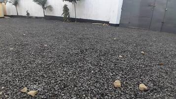 Un sol recouvert de gravier, parsemé de rochers et de petits arbres.