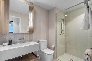 Ein modernes Badezimmer mit einer Duschkabine aus Glas, einem weißen Waschbecken und einer Toilette.
