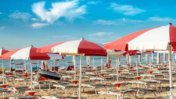 Ein Strand mit Liegestühlen und roten und weißen Strandmuscheln.