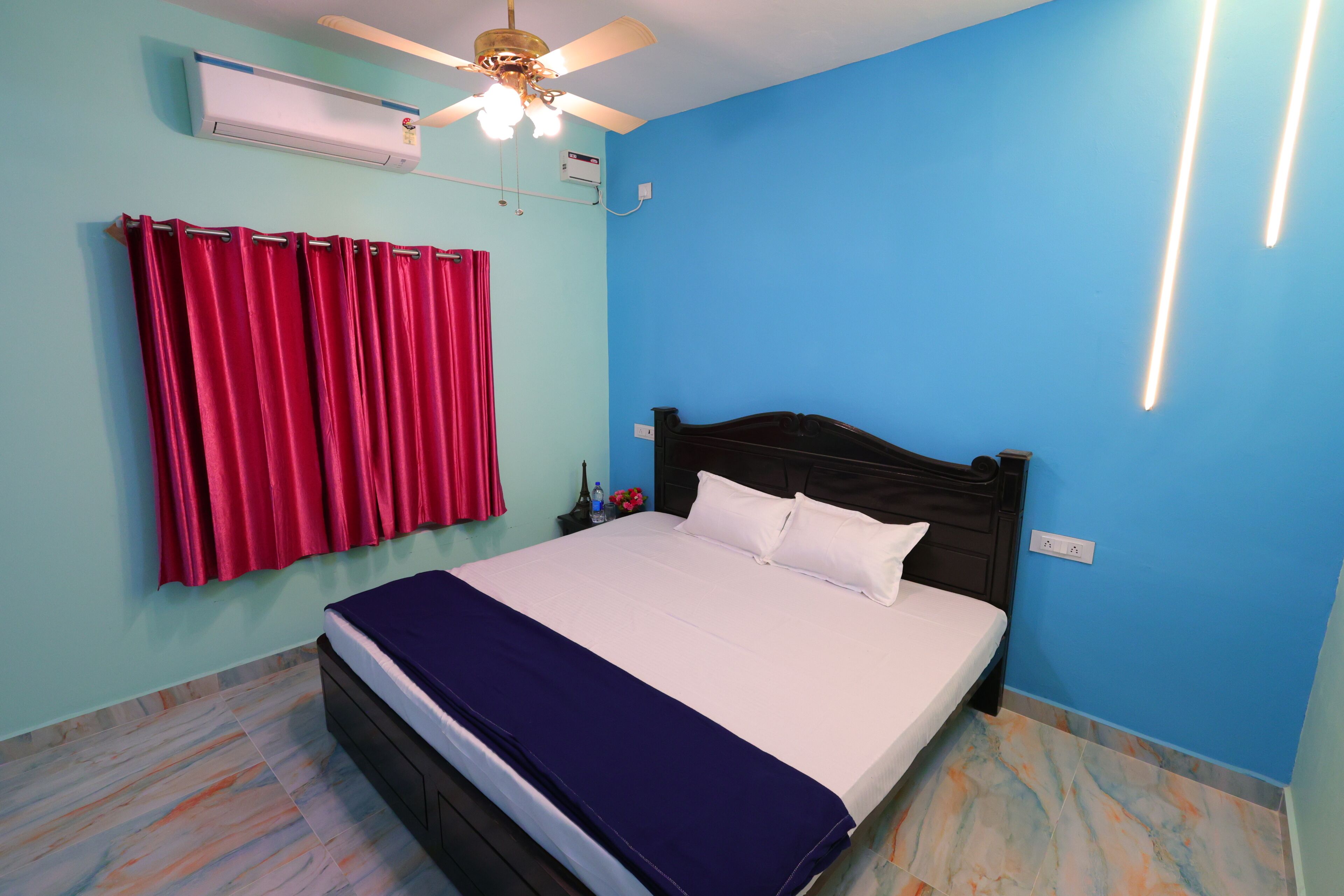 Ein Schlafzimmer mit einem Bett, einem Deckenventilator, einer Klimaanlage und einer Wandleuchte.