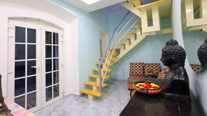 A modern interior with a staircase, a Buddha statue, and a decorative bowl. - Nautical Escape Homestay - Pondicherry (Puducherry)