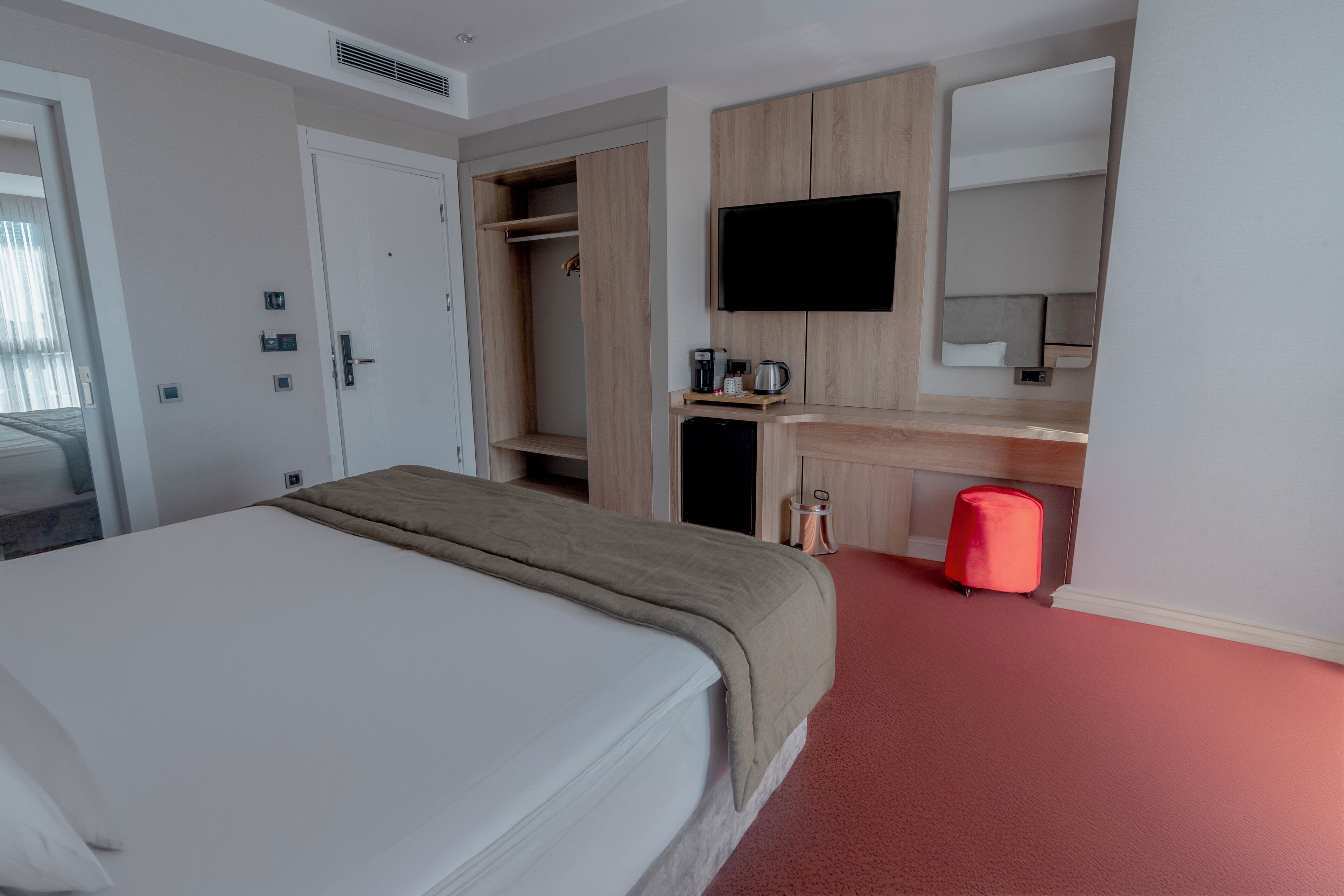 Una habitación de hotel con cama, escritorio, televisor y armario.