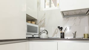 A kitchen with white cabinets, a microwave, a kettle, and a sink. - Flower apartment - new bright home in Brera (milano)