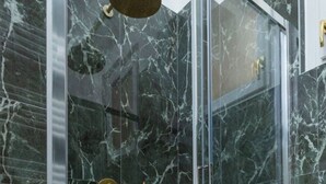 A bathroom with marble walls and a glass shower enclosure. - Flower apartment - new bright home in Brera (milano)