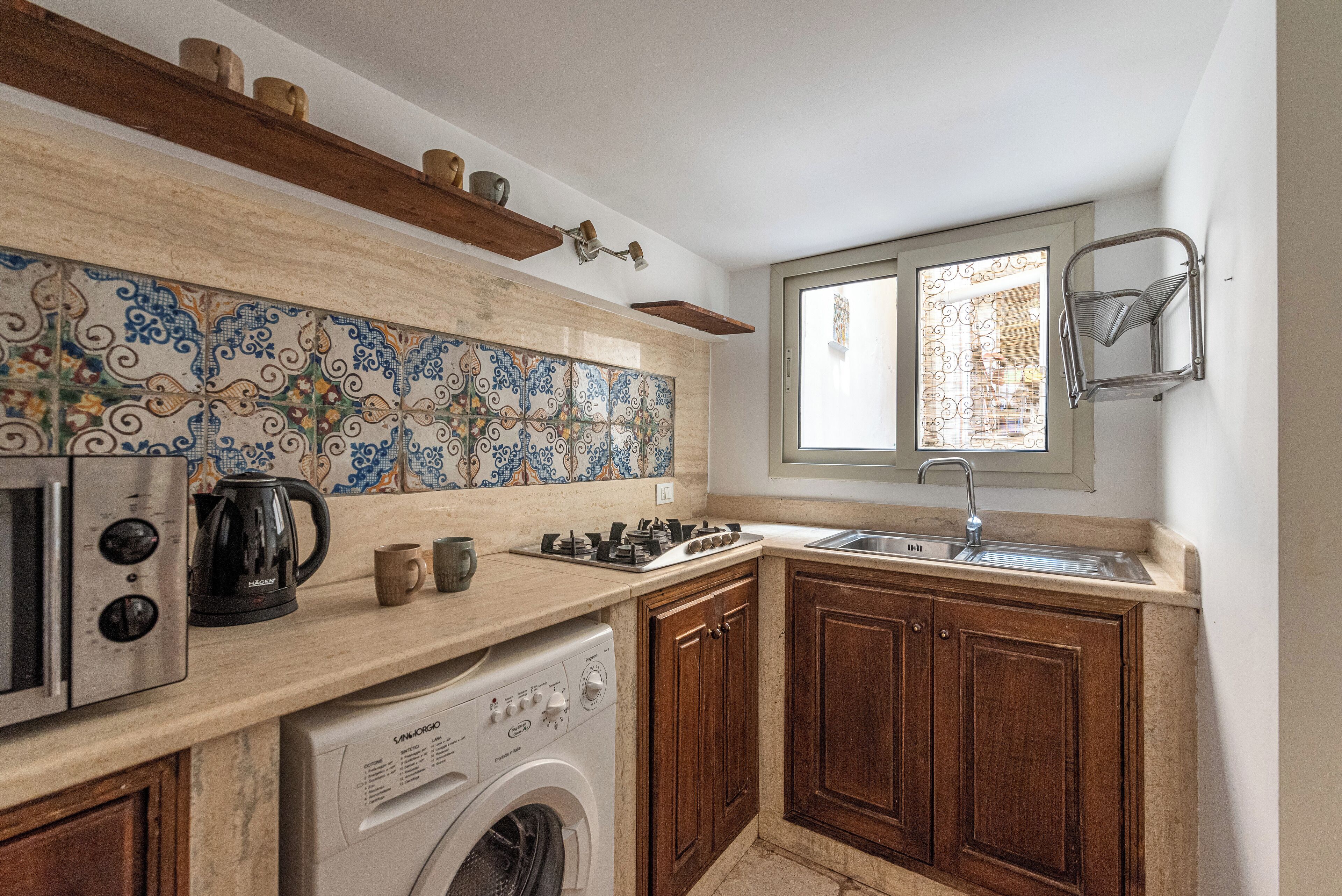 A compact kitchen with a washing machine, a coffee maker, and a sink.