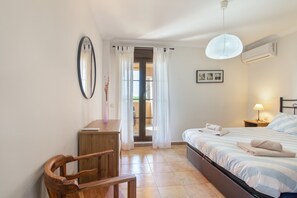 A bedroom with a bed, a desk, a chair, a window with curtains, and a hanging light fixture. - Apartment 'Albatros' with Shared Pool, Private Terrace and Wi-Fi (Ayamonte)