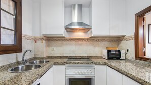 A kitchen with a stainless steel range hood, a microwave, a double sink, and a built-in oven. - Apartment 'Albatros' with Shared Pool, Private Terrace and Wi-Fi (Ayamonte)