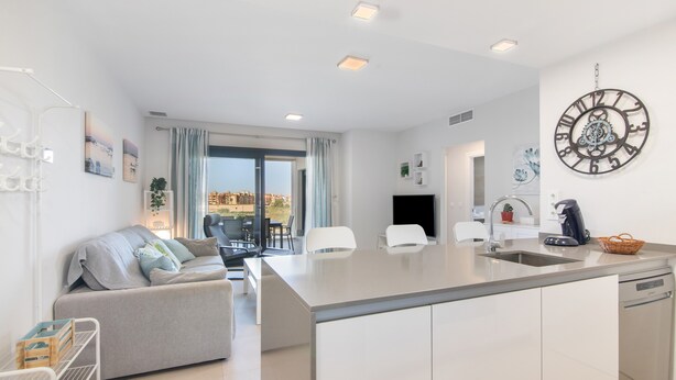 A modern kitchen with a central island, a dining area with a sofa, and a view of the city. - Apartment 'Los Flamencos' with Sea View, Wi-Fi and Air Conditioning (Isla Canela)