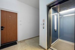 A hallway with a wooden door labeled '2' and an elevator with a fire safety sign.