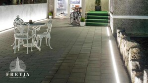 Un edificio moderno con facciata in vetro, un albero illuminato e posti a sedere all'aperto.
