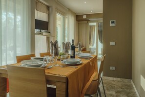 A dining area with a long table set for a meal, featuring plates, glasses, and a bottle of wine. -  Hotiday Lodge Cecina (Cecina)