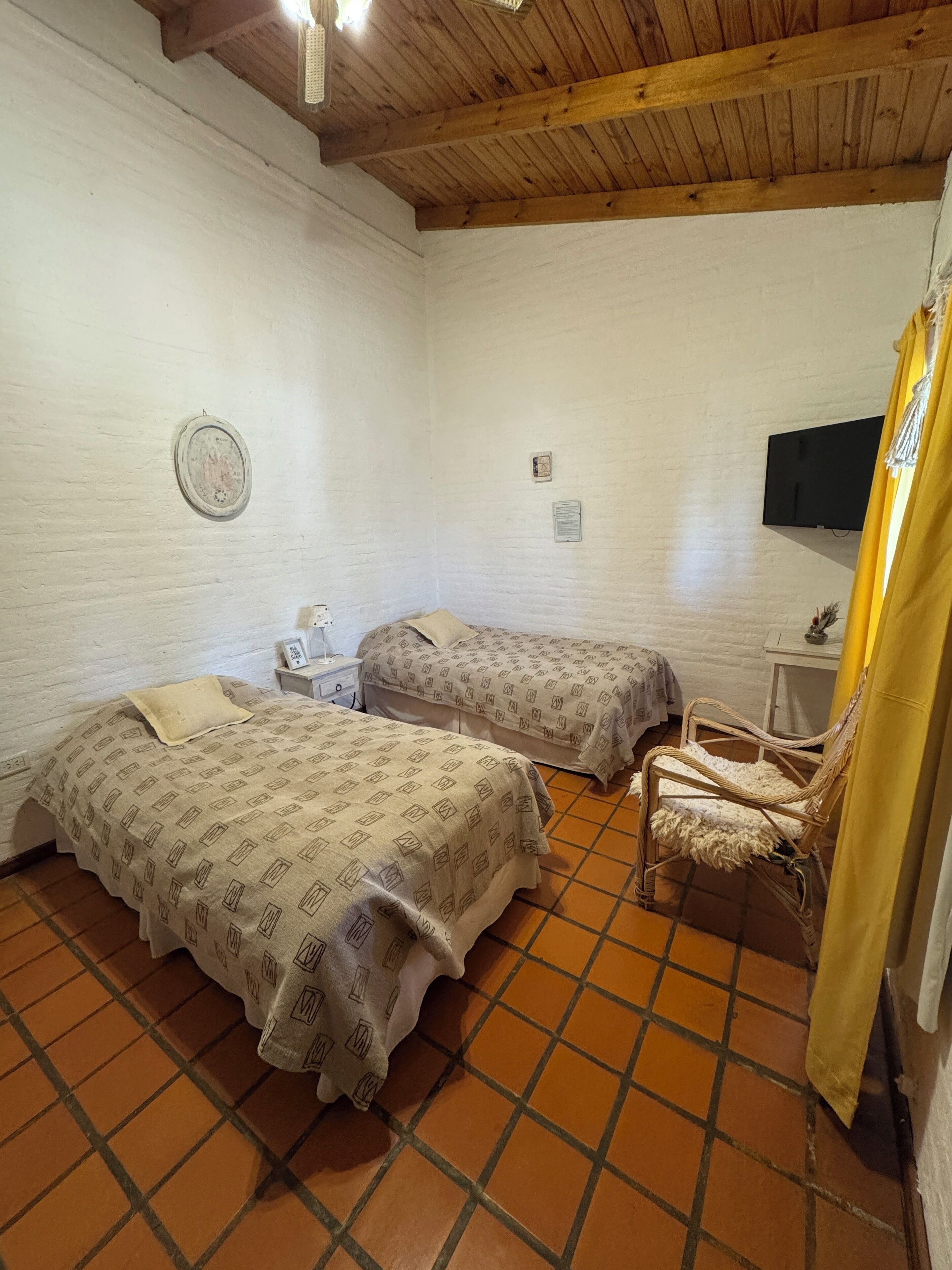 A room with two beds, a chair, a small table, and a television.